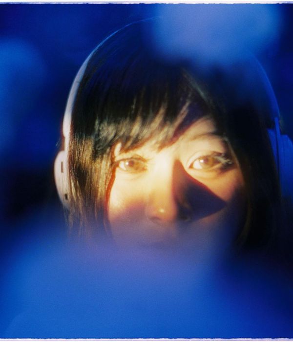 A serene woman with eyes closed, focusing inward, against a dark background with blue light.